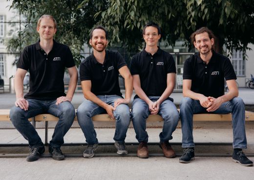 Die vier Gründer der Space StartUps ARTI sitzen auf einer Bank und lächeln in die Kamera. 