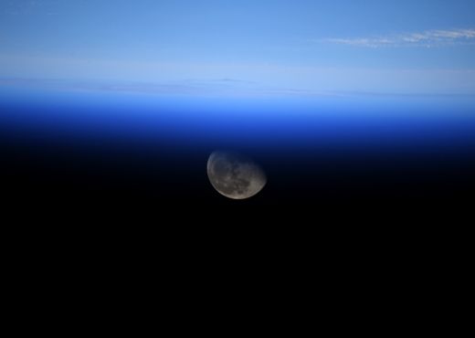 Der Mond ist zur Hälfte über dem Horizont der Erde sichtbar. 