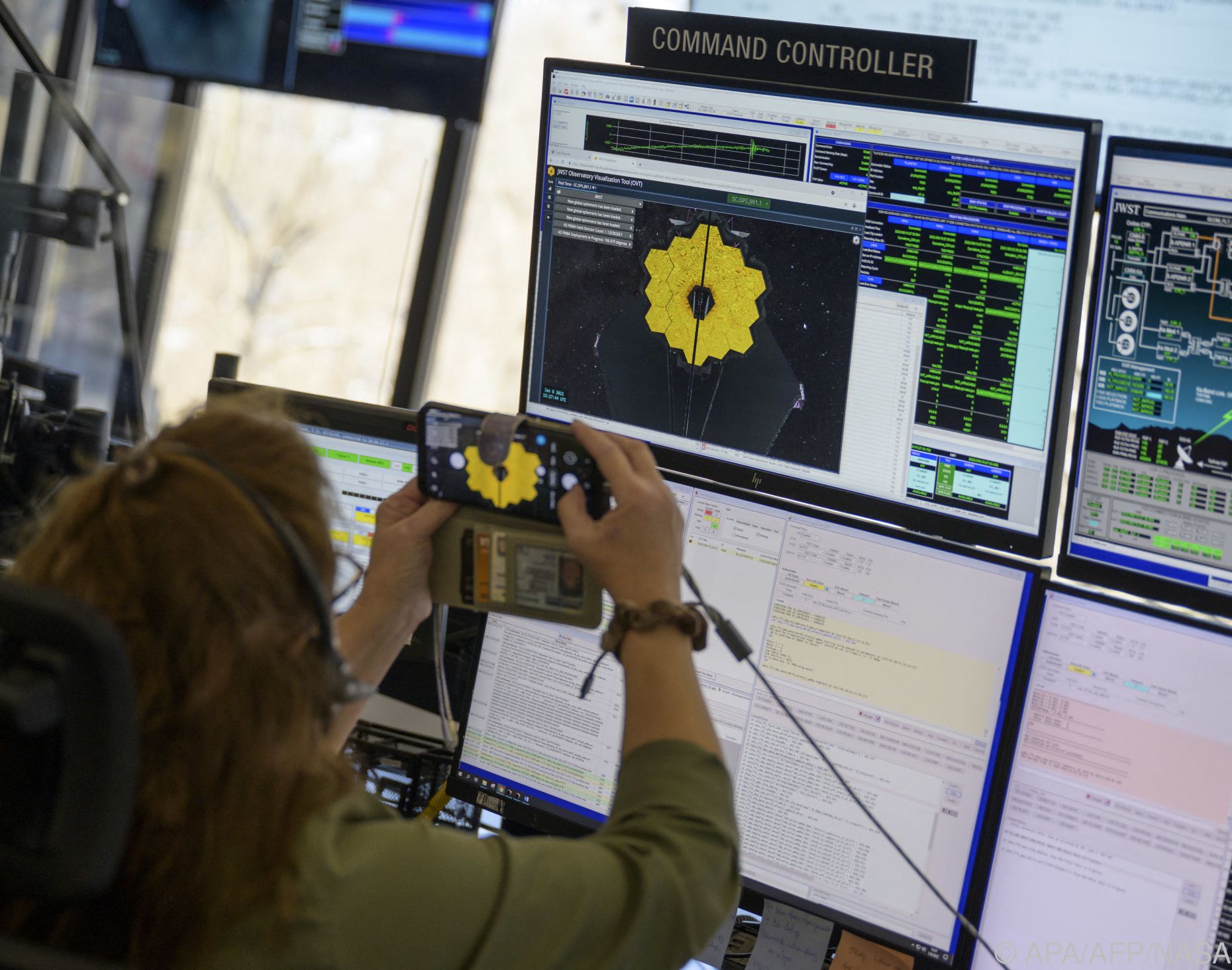 NASA Mitarbeiter im Control Room vor einem Bildschirm, der das Webb Teleskop zeigt 