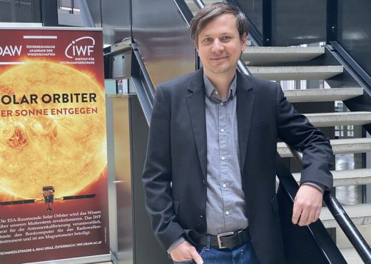 IWF-Forscher Christian Möstl vor einem Plakat über Sonnenstürme