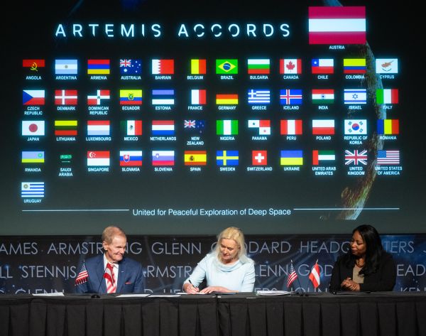 Botschafterin Petra Schneebauer, NASA Administrator Bill Nelson und die stellvertretende Außenministerin der Vereinigten Staaten Jennifer R. Littlejohn mit den Flaggen aller Beitrittsländer bei der Unterzeichnung des Artemis Accord Abkommens