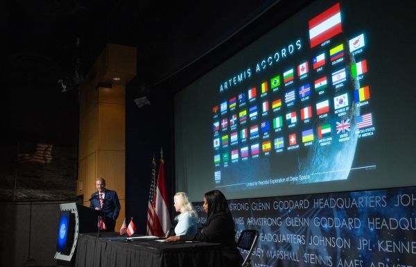 Botschafterin Petra Schneebauer, NASA Administrator Bill Nelson und die stellvertretende Außenministerin der Vereinigten Staaten Jennifer R. Littlejohn am Podium mit den Flaggen der Beitrittsländer im Hintergrund