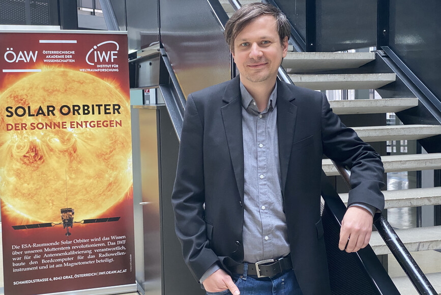 IWF-Forscher Christian Möstl vor einem Plakat über Sonnenstürme